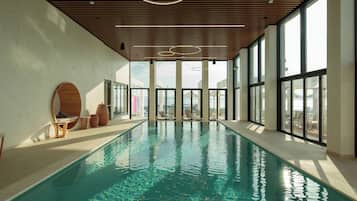 Una piscina techada, una piscina al aire libre, sombrillas