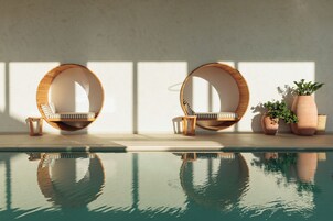 Una piscina techada, una piscina al aire libre, sombrillas