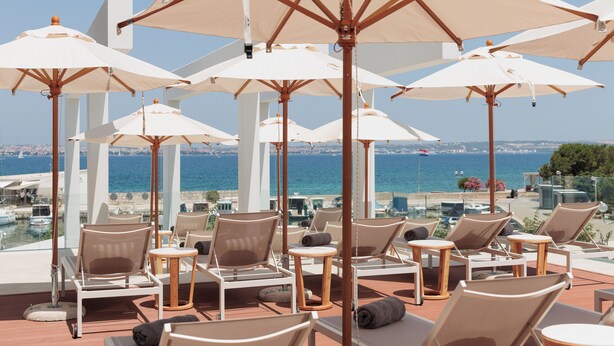 A terrace with sun loungers and umbrellas overlooking the sea. - Hotel Preko Ugljan Island, Curio Collection By Hilton (Preko)