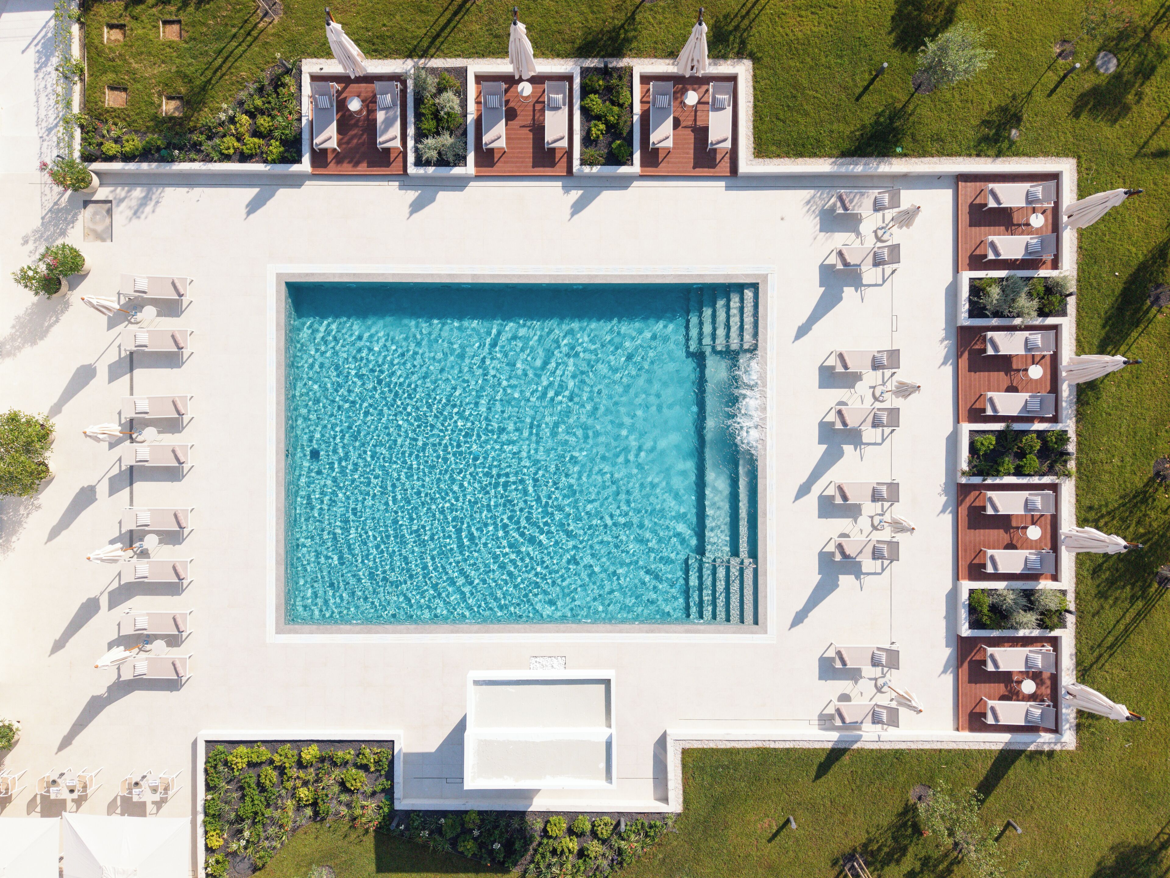 An aerial view of a swimming pool area with multiple lounge chairs and a rectangular pool.