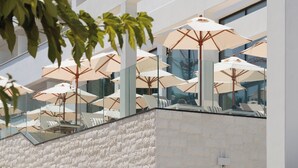 A modern building with a stone facade, outdoor seating with umbrellas, and large windows. - Hotel Preko Ugljan Island, Curio Collection By Hilton (Preko)