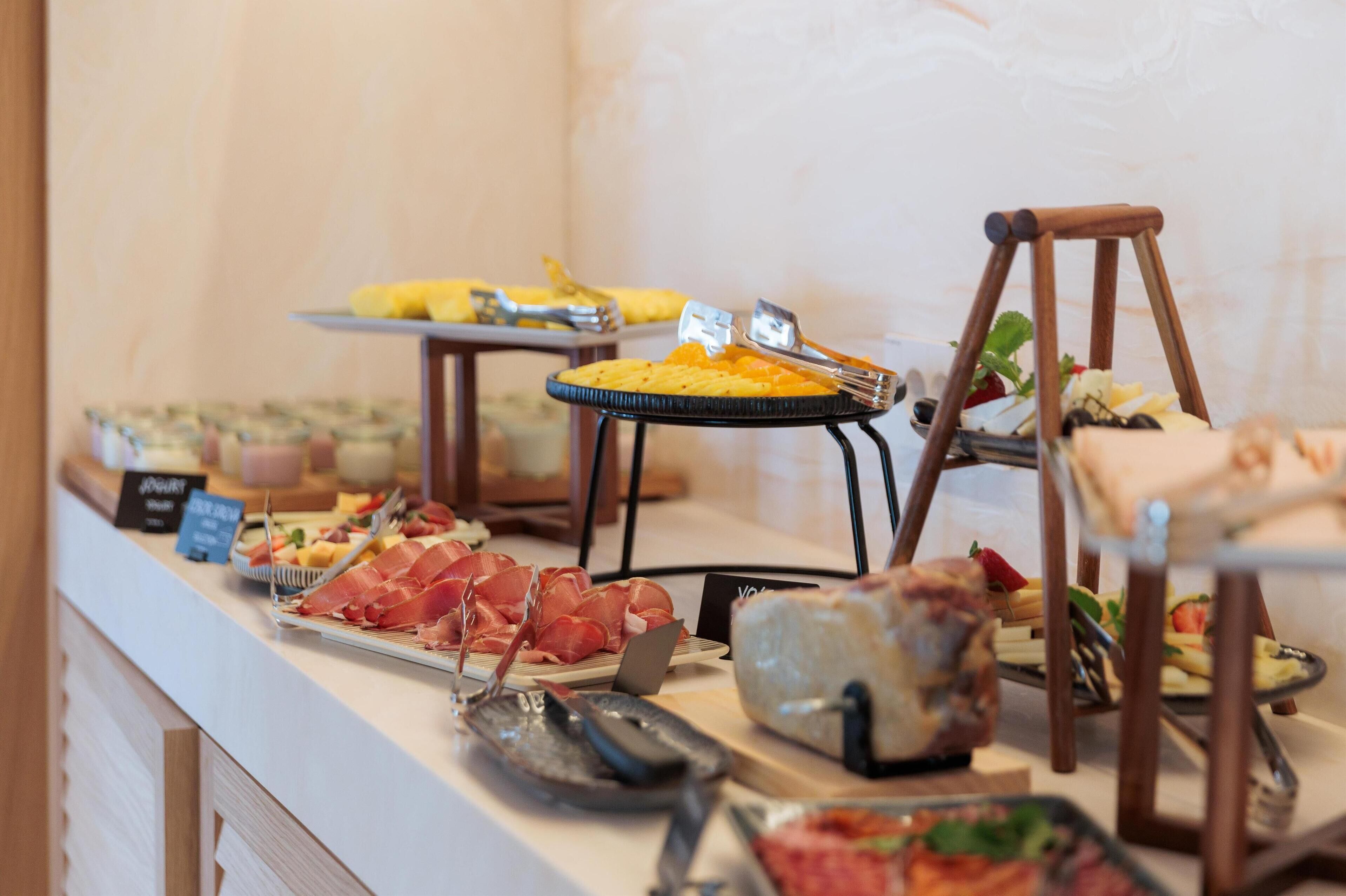 A buffet with various food items including meats, cheeses, and fruits.