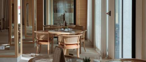 A modern dining area with wooden furniture and large windows.