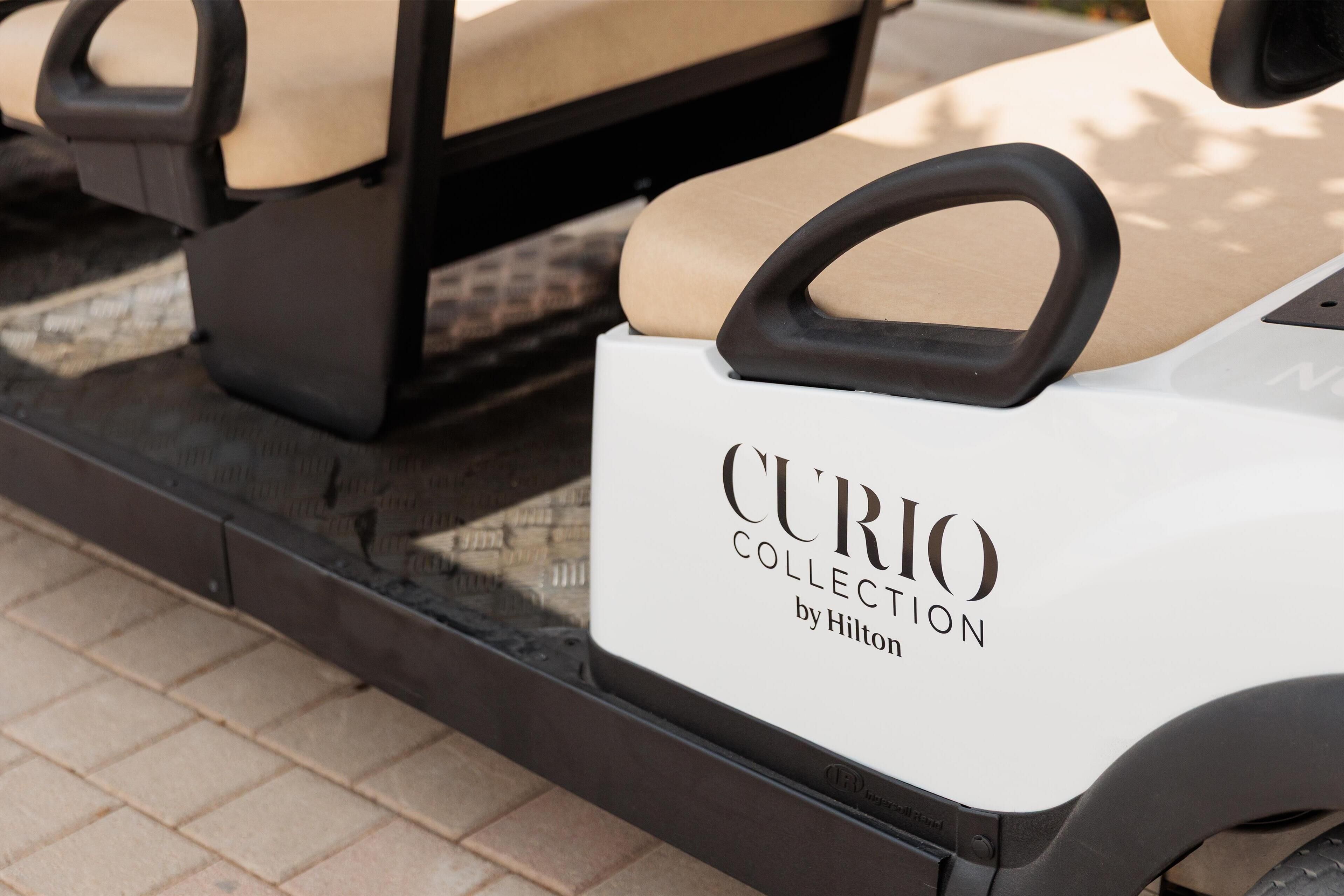 A golf cart with a sign that reads "CURIO COLLECTION by Hilton."