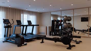 Un gimnasio moderno con cintas de correr, elípticas y pesas libres.