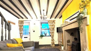 Un salon avec une cheminée, un canapé, un tapis et une fenêtre avec des rideaux.