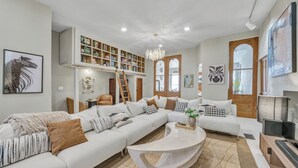 Un salon spacieux avec un grand canapé d’angle, une table basse et une bibliothèque remplie de livres et d’objets décoratifs.