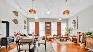Un salon spacieux doté d’une cheminée, de parquets en bois et d’une grande fenêtre agrémentée de rideaux.
