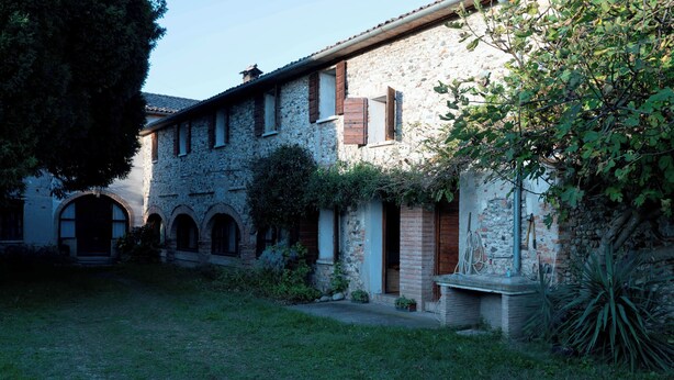 A stone building with arched doorways and a small garden area. - Montello Hill front property with large garden (Ciano)