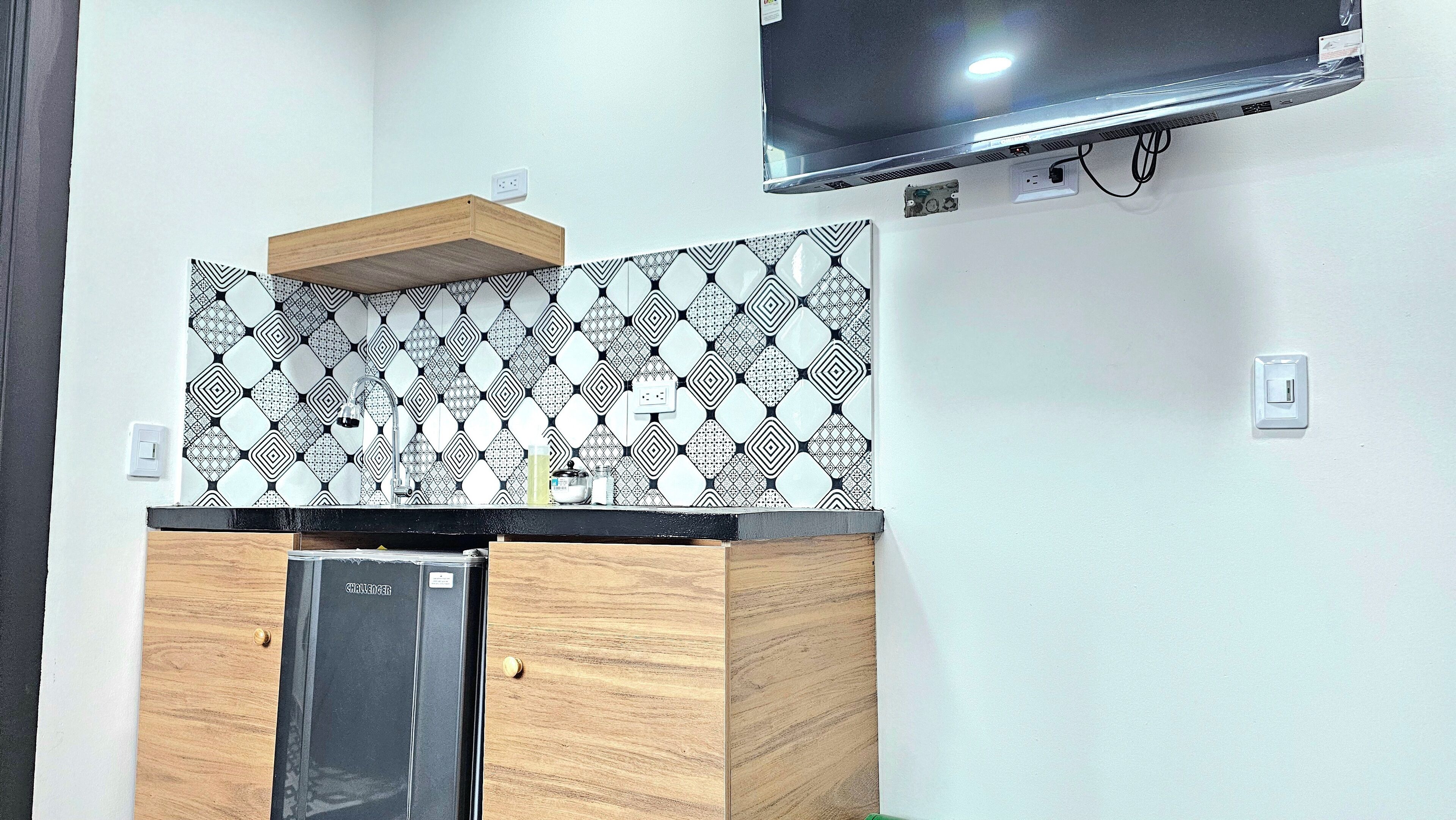A kitchen with a built-in dishwasher, a wooden countertop, and a patterned backsplash.
