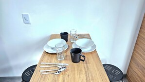 A dining table set with plates, glasses, cutlery, and a black mug. - Hotel Ktaleya Apartamentos (Bogotá)