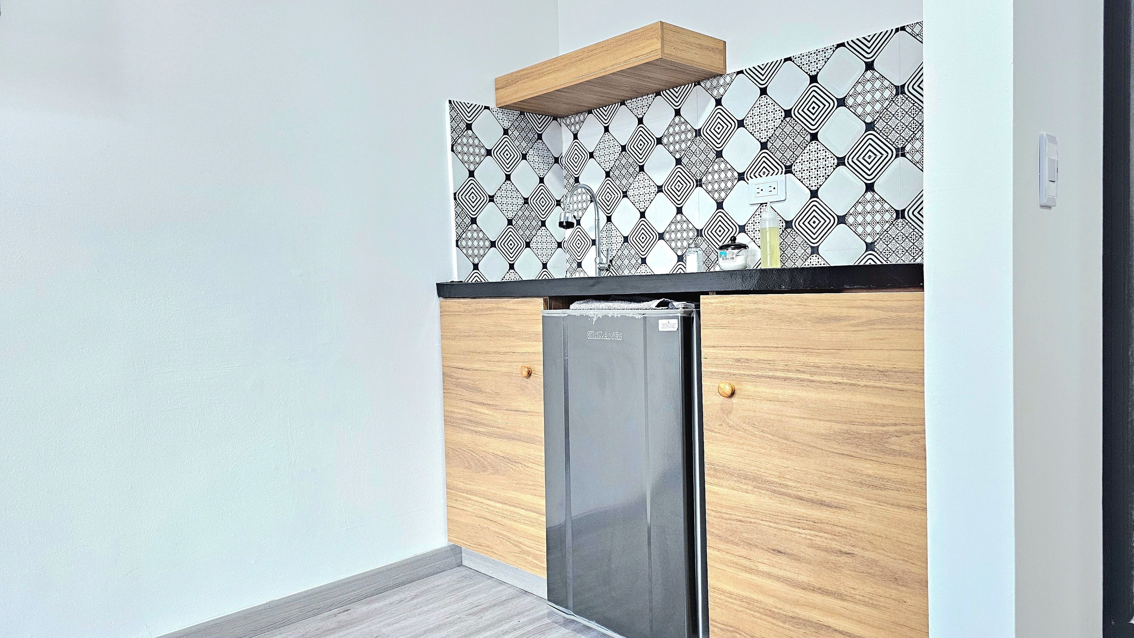 Una cocina con un salpicadero de diseño, un armario de madera y un refrigerador de acero inoxidable.