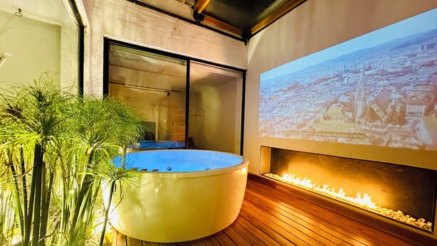 Un espace spa moderne doté d’un jacuzzi, d’un plancher en bois et d’une projection d’un paysage urbain sur le mur.