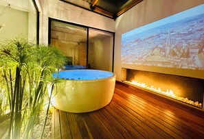A modern spa area with a hot tub, wooden flooring, and a projection of a cityscape on the wall.