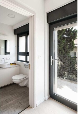 Un bagno moderno con lavandino, water e un'ampia finestra bianca.