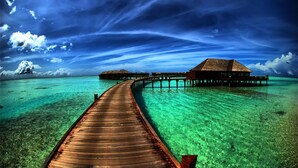 Muelles de madera que conducen a bungalows sobre el agua, con aguas turquesas cristalinas.