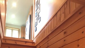A wooden staircase with a handrail, leading to a landing with a door and a wall-mounted picture frame. - Cozy 4-bedroom cabin with views of Saddleback mountain- WiFi plus an EV charger (Dallas Plantation)