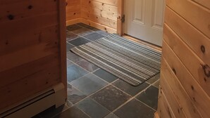 A wooden interior hallway with a door leading outside, a small window, and a doormat. - Cozy 4-bedroom cabin with views of Saddleback mountain- WiFi plus an EV charger (Dallas Plantation)