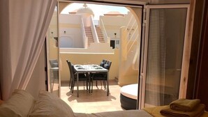 Un dormitorio con cama, ventana y vista a un área de comedor al aire libre.