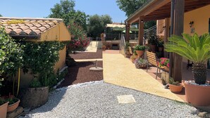 Une cour dotée d’un toit en tuiles, de plantes en pot et d’une pergola surmontée d’un panneau solaire.