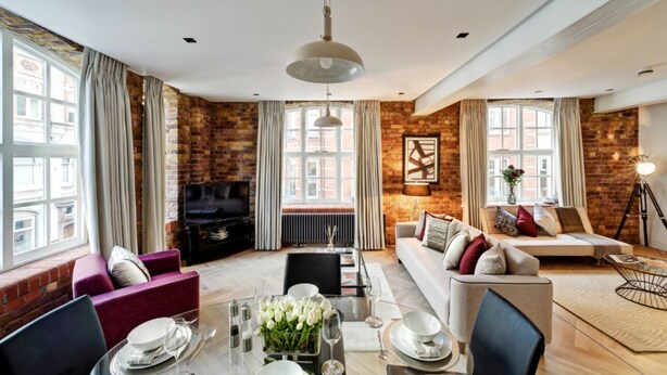 A modern living room with a fireplace, a dining area with a table set for four, and a sofa set.