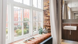A bathroom with a large window, a radiator, and a sink.