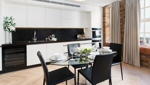 A modern kitchen with white cabinets, a black countertop, and a dining area with a glass table and black chairs.