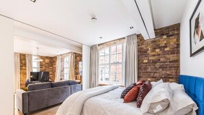 A modern bedroom with a large bed, a blue headboard, and a grey sofa.
