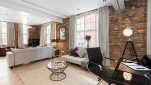 A modern living room with a sofa, a coffee table, and a desk with a lamp.
