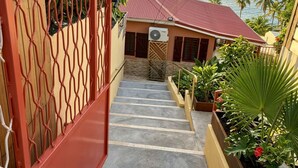 A staircase leading to a building with a red roof, surrounded by plants and overlooking the sea. - Old family home renovated for holidaymakers (Basse-Terre)