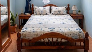 A bedroom with a wooden bed, a mosquito net, a potted plant, and a window with curtains. - Old family home renovated for holidaymakers (Basse-Terre)