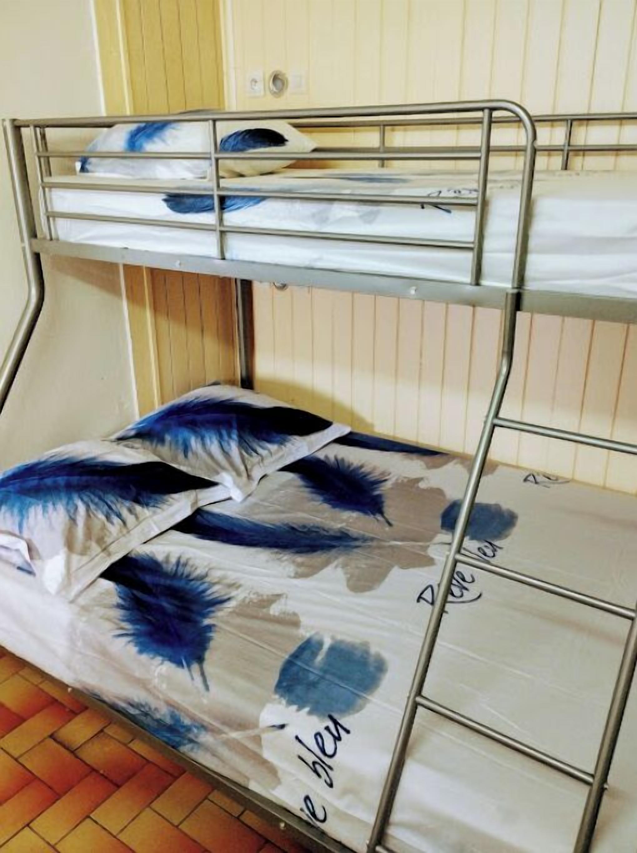 Ein Etagenbett mit einer unteren Schlafgelegenheit und einer Matratze mit blau-weißer Musterung.