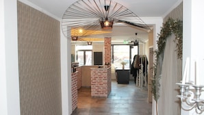 A hallway with a brick reception desk, a chandelier, and a wall with a patterned wallpaper.