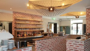 A bar area with a brick wall, shelves of glasses, and a variety of bottles.
