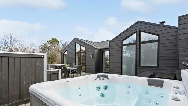 A hot tub in a backyard with a patio and a house in the background.