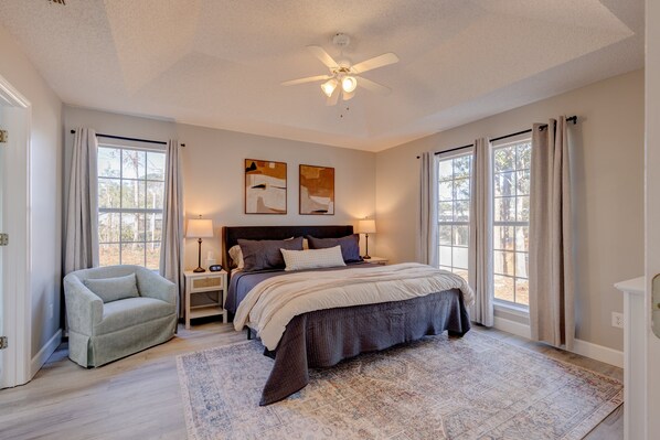 A bedroom with a bed, a nightstand, a chair, and a ceiling fan. - Tall Timbers Waterfront Oasis: 3BR / 2 BATH Retreat with Garage (Thomasville)