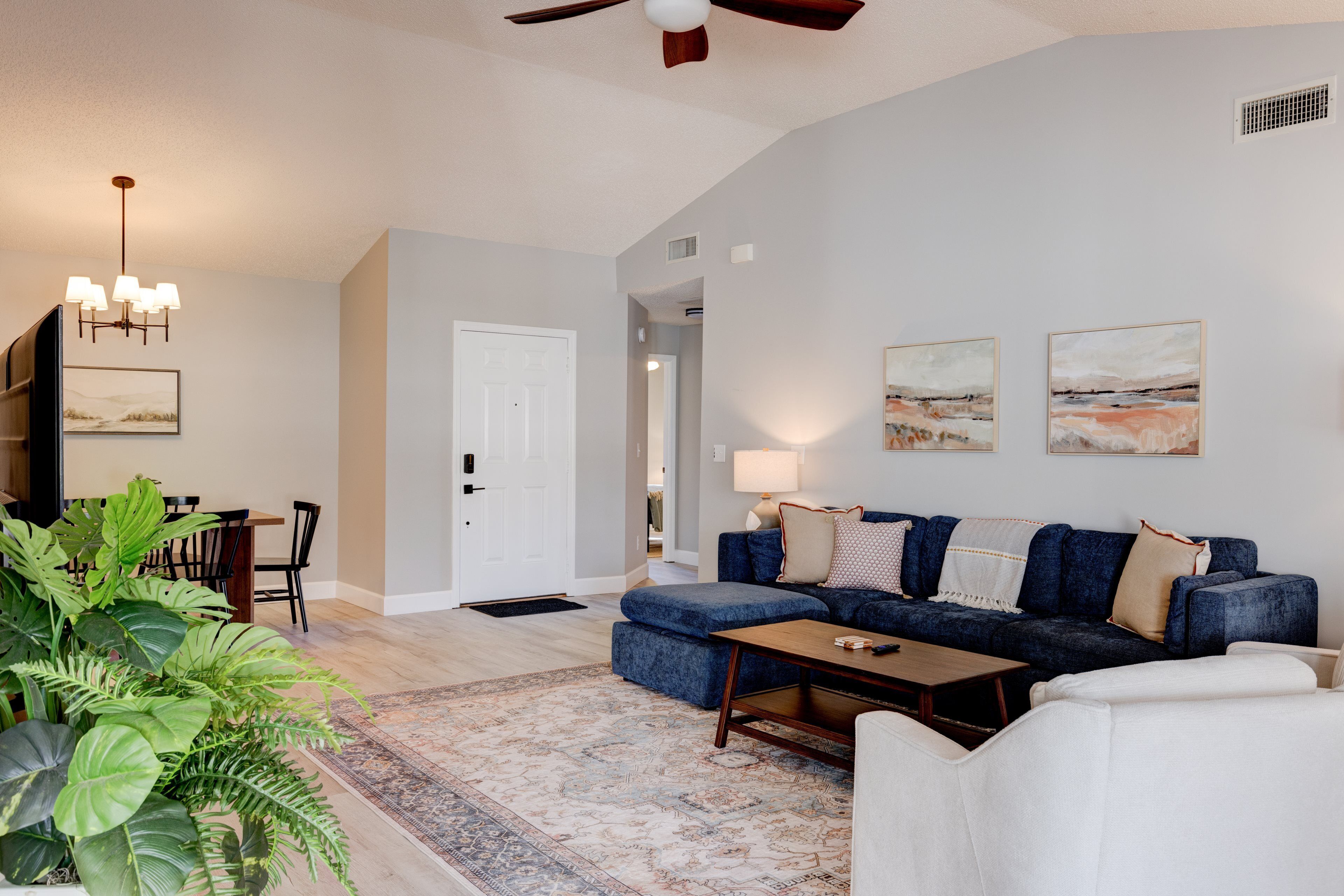 A living room with a sofa, ottoman, coffee table, and a dining area with chairs and a table.