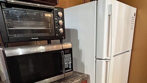 A kitchen with a built-in microwave, a toaster oven, and a white refrigerator.