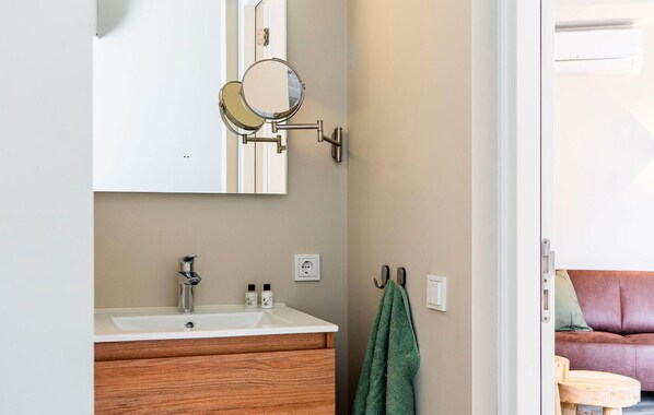 Une salle de bain avec un meuble-lavabo en bois, un miroir et une serviette accrochée au mur.