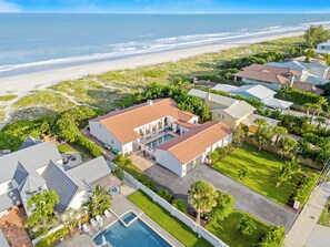 A residential area with a large house featuring a swimming pool, surrounded by lush greenery and a view of the beach. - Ocean front Luxury Hacienda with pool,  pet friendly 5 (Cocoa Beach)