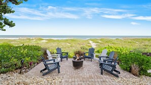 A patio with Adirondack chairs, a fire pit, and a view of the beach and dunes. - ⭐️⭐️Ocean front Luxury Hacienda with pool,  pet friendly 5⭐️🏖️ (Cocoa Beach)