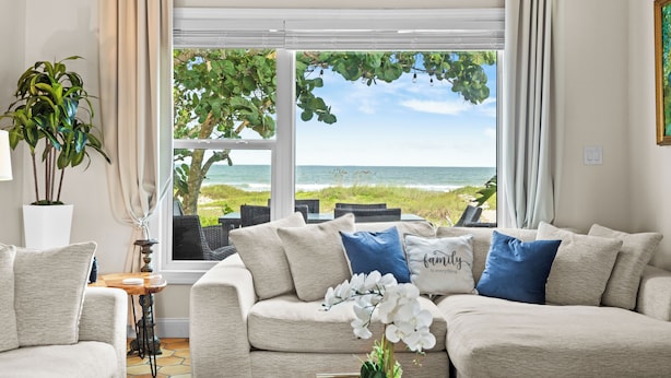 A living room with a view of the ocean, a potted plant, and a sofa with decorative pillows. - ⭐️⭐️Ocean front Luxury Hacienda with pool,  pet friendly 5⭐️🏖️ (Cocoa Beach)