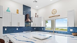 A modern kitchen with a large island, white cabinets, blue backsplash, and a view of the ocean. - ⭐️⭐️Ocean front Luxury Hacienda with pool,  pet friendly 5⭐️🏖️ (Cocoa Beach)