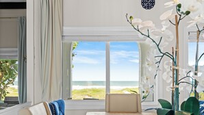 A room with a view of the beach, a potted orchid, a blue chair, and a table. - ⭐️⭐️Ocean front Luxury Hacienda with pool,  pet friendly 5⭐️🏖️ (Cocoa Beach)