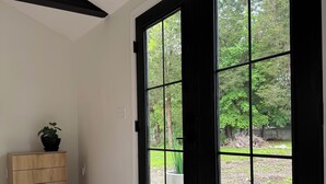 Una habitación con una puerta negra grande, un armario de madera y vistas a un jardín.