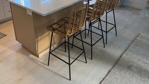Una cocina moderna con una isla grande, taburetes de bar y vistas al exterior.