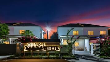 A hotel with a well-lit entrance, a signboard, and a clear view of the sky.