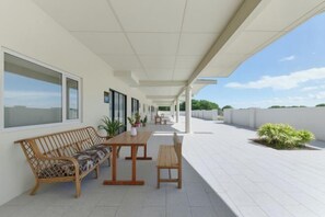 Un patio al aire libre con una mesa, sillas, un sofá y plantas en macetas.