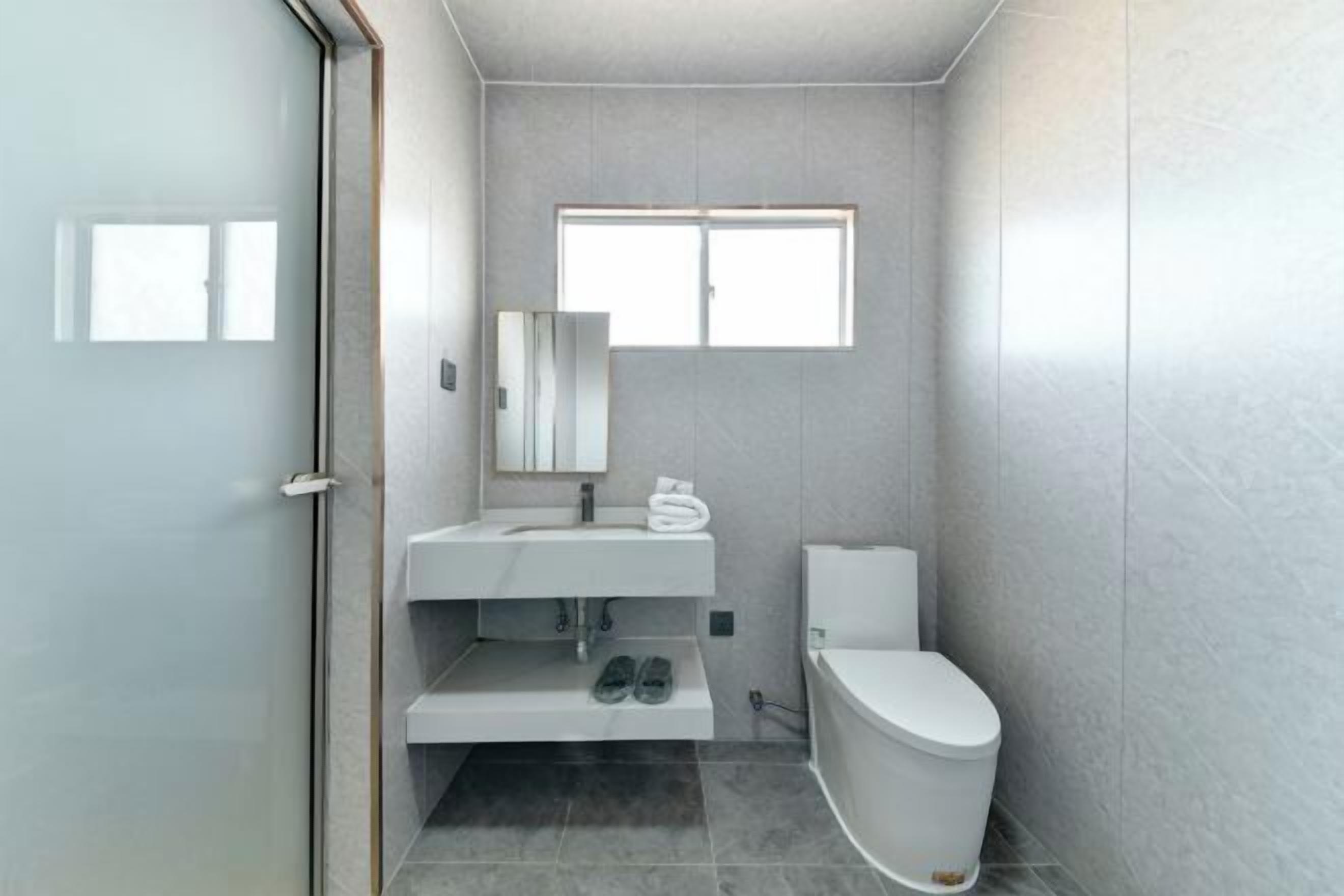 A bathroom with a toilet, sink, and mirror.