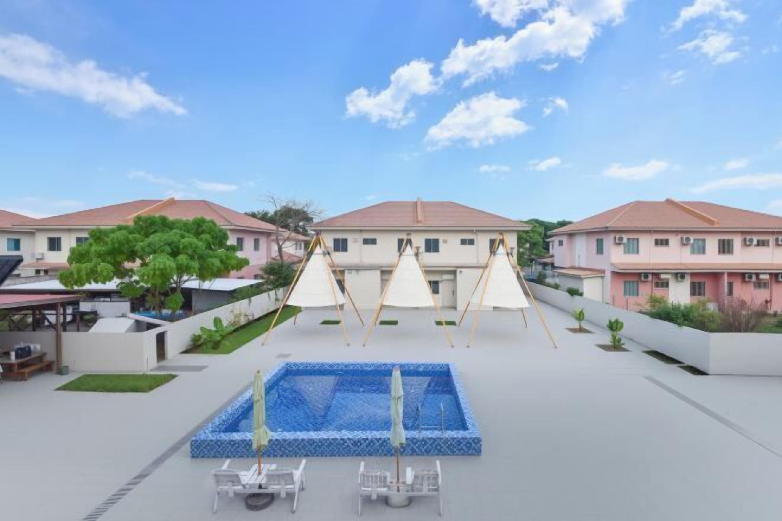 A hotel courtyard with a swimming pool, lounge chairs, and a swing set.